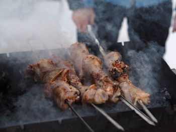 Men fry on the street in winter on skewers on coals and open fire.blurred image from steam 