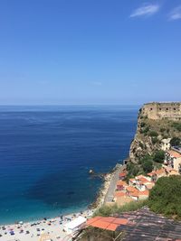 High angle view of townscape by sea against blue sky