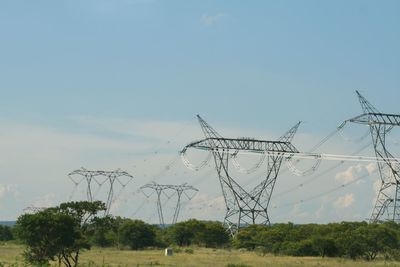 Electricity pylon on field against sky