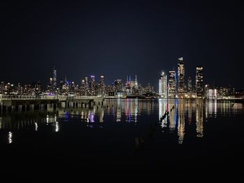 River by illuminated buildings against clear sky at night