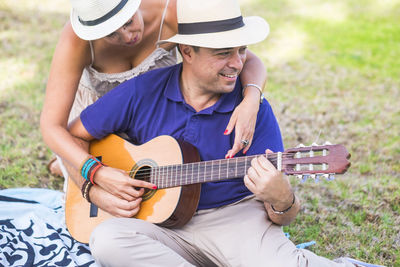 Man playing guitar while woman embracing