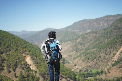 Rear view of man looking at mountains against sky