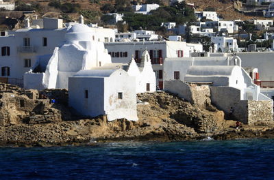 Buildings by sea against sky