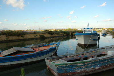 Boats moored at harbor against sky