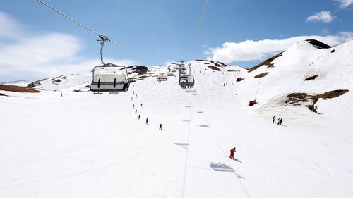 Ski lift on snowcapped mountains against sky