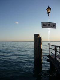 Information sign by sea against sky