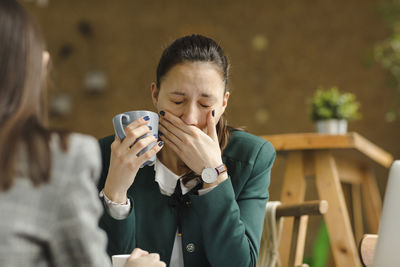 Woman using phone while holding coffee cup