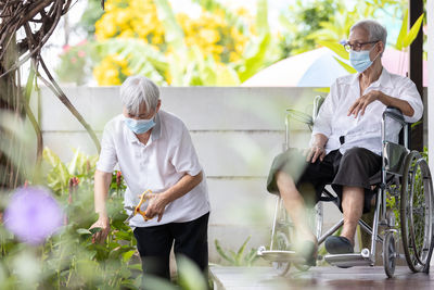 Rear view of people standing against plants