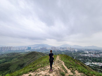 Rear view of man standing on mountain against sky