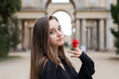 Portrait of beautiful woman holding red flower