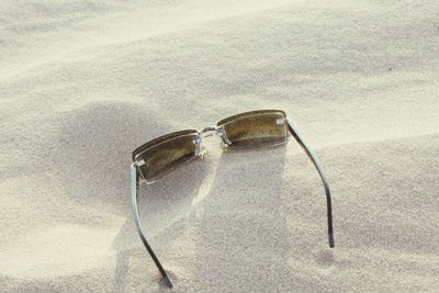 High angle view of eyeglasses on sand