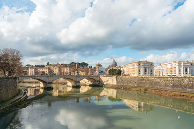 Arch bridge over river against buildings in city