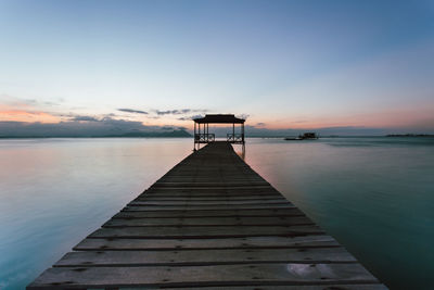 Pier over sea against sky during sunset