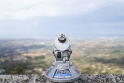 Coin-operated binoculars on mountain against sky