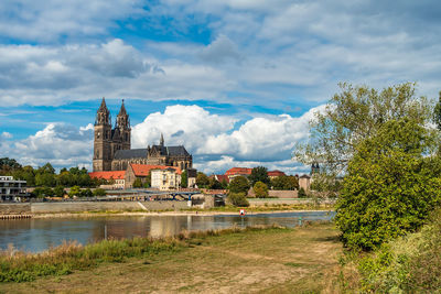 Built structure by river and buildings against sky