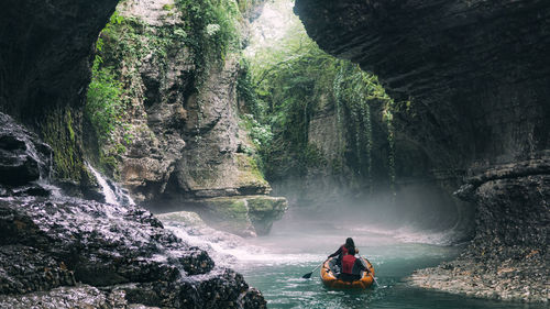 Rear view of man on rock against waterfall