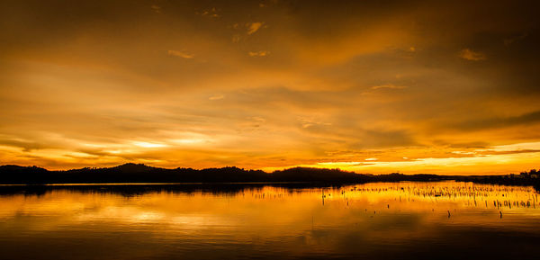 Scenic view of lake against dramatic sky during sunset