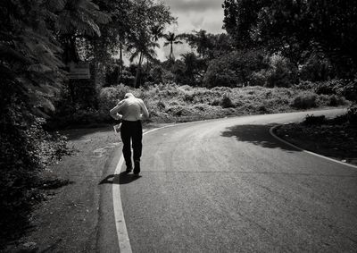 Rear view of a man walking on road