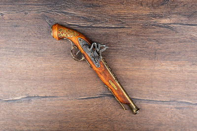 Mock up of an old pistol with bronze inlay on a wooden background.