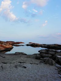 Scenic view of rocky shore at beach against sky
