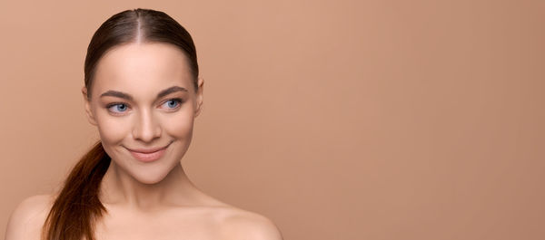 Portrait of young woman against pink background