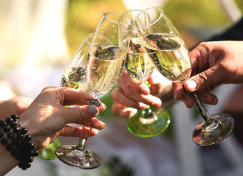 Cropped hands of friends toasting champagne flutes in party