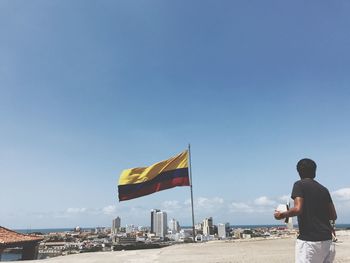 Rear view of man standing by colombian flag in city