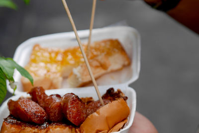 Close-up of hand holding burger in plate