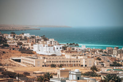 High angle view of townscape by sea against sky