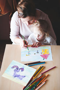 High angle view of mother drawing with daughter at table