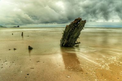 Scenic view of beach against cloudy sky