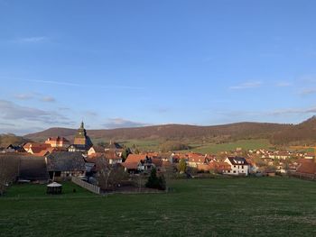 Houses on field by town against sky in ershausen, schimberg, eichsfeld, thuringia, germany