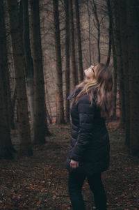 Woman looking up while standing in forest