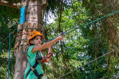 Adventure climbing high wire park - people on course in mountain helmet and safety equipment