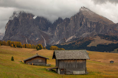 House on field by mountain against sky