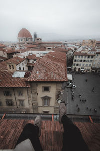 Low section of man on roof against sky in city