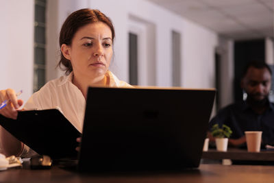 Young woman using laptop while sitting at office
