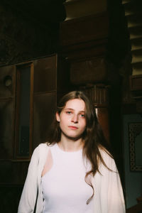 Portrait of young woman standing against wall