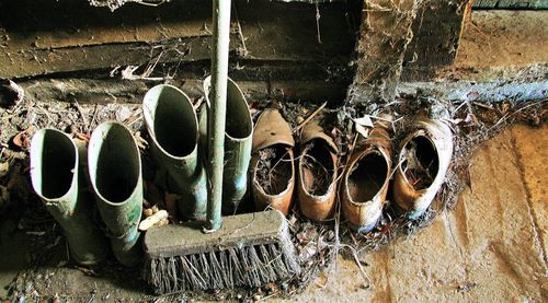 High angle view of damaged shoes with broom in abandoned room