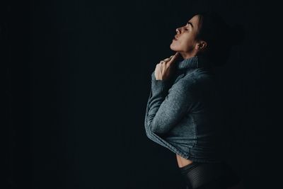 Smiling woman wearing sweater while posing against gray background