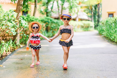 Full length of sisters holding hands walking on street