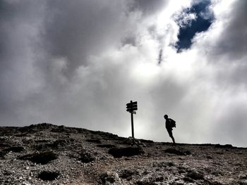 Person standing on landscape against cloudy sky