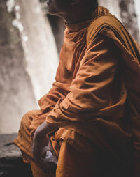 Midsection of man sitting on cross