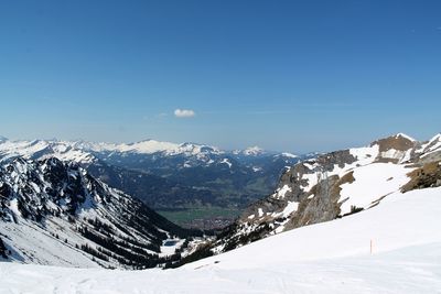 Scenic view of snowcapped mountains against blue sky