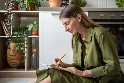 Side view of young woman using mobile phone at home