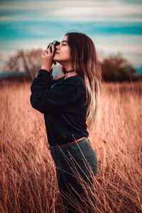 Woman photographing while standing on field