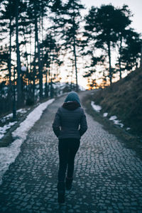 Rear view of woman walking on road in forest
