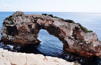 Rock formations on sea shore against sky