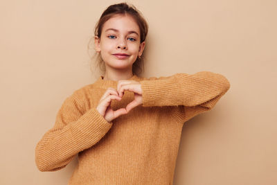 Portrait of young woman standing against pink background