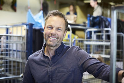 Portrait of smiling mature man standing in illuminated warehouse